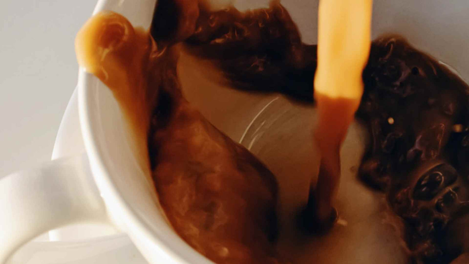 Hot NUJO being poured into a white mug.