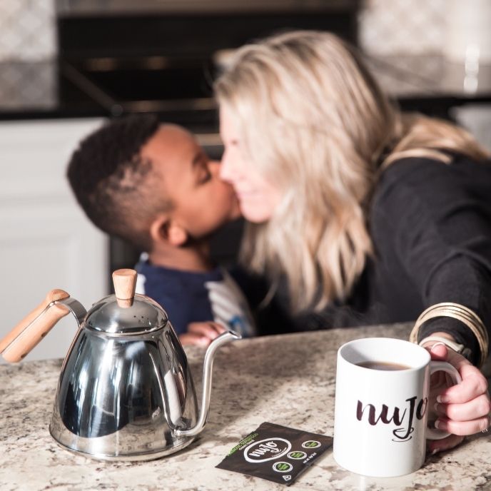 The female founder of NUJO with her adopted son, posing with a NUJO mug.